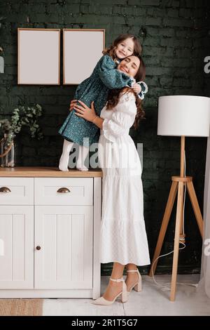 Giorno della mamma. Giovane mamma sensibile abbraccia a casa sua piccola adorabile figlia. Fiducia, sostegno e amore tra mamma e bambino. Amiamo la famiglia godere Foto Stock