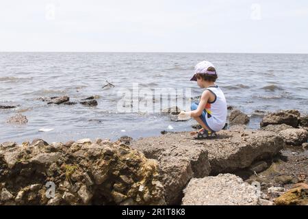 bambino che guarda il fiume inquinato dalla riva, concetto ambientale Foto Stock