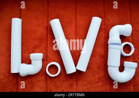 L'iscrizione amore è composto da bianco, idraulico, tubi di plastica, raccordi, flange, guarnizioni in gomma sullo sfondo di un tappeto rosso. Una parola d'amore Foto Stock