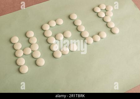 Bella iscrizione aiuto fatto da bianco rotondo liscio pillole mediche, vitamine, antibiotici e spazio copia su uno sfondo blu brillante. Giacitura piatta. Foto Stock