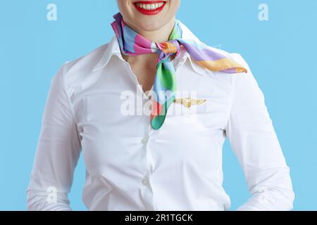 Primo piano su elegante e sorridente stewardess femminile isolato su sfondo blu in uniforme. Foto Stock