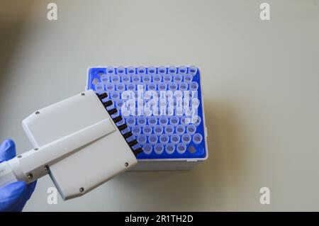 Uno scienziato di laboratorio con un dispenser in mano conduce esperienze o analisi. Foto Stock