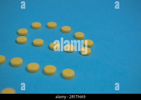 le pillole gialle sono disposte su uno sfondo blu colorato sotto forma di lettere rotonde. le iscrizioni volumetriche sullo sfondo sono fotografate da t Foto Stock