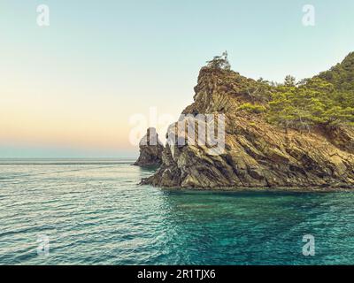 verdi montagne con piante in alto nel mare. una roccia in acqua, una piccola isola per i marinai. località turistica. viaggi in paesi caldi. Foto Stock