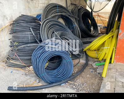 Molte grandi bobine di cavi neri in isolamento in plastica o fili elettrici per l'elettricità in un magazzino industriale. Foto Stock