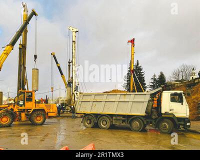 attrezzature da costruzione nel sito di riparazione del cavalcavia. alta, la gru sostiene il palo per la costruzione di un enorme cavalcavia. accanto a un autocarro pesante con Foto Stock