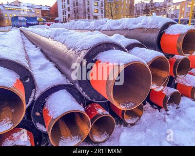 tubi lunghi, neri, stretti per la posa di comunicazioni idrauliche. i tubi metallici sono ricoperti da uno strato di neve. la gente cambia tubi nella stagione fredda. Foto Stock