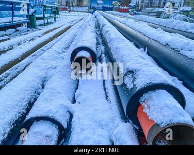 materiale per interventi di riparazione. tubi fognari per la posa delle comunicazioni. tubi lunghi in polipropilene nero su neve bianca pulita. Foto Stock
