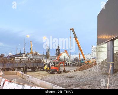 costruzione di un ponte rotto su una strada trafficata. i carrelli pesanti hanno portato un telaio in metallo per il sorpasso. una gru arancione trasporta i blocchi ad un'altezza per co Foto Stock