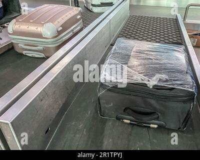 bagaglio sul nastro all'aeroporto. la valigia viaggia lungo la linea. le cose sono impilate. la valigia è confezionata in pellicola trasparente. sicurezza e. Foto Stock