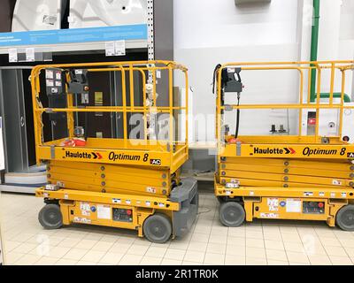 Grande sollevatore idraulico mobile giallo su ruote per il sollevamento e lo spostamento di persone e carichi su scaffali in un supermercato in magazzino. Bielorussia, Minsk, ottobre Foto Stock