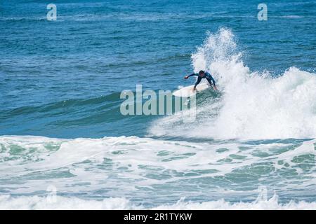 Il giovane surfista atletico cavalca l'onda a Furadouro Beach a Ovar, Portogallo. Foto Stock