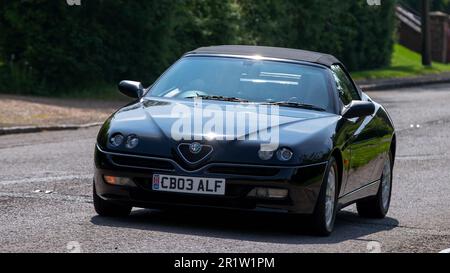 Stoke Goldington, Northants, Regno Unito - Maggio 14th 2023. 2003 nera ALFA ROMEO RAGNO auto classica guida attraverso un villaggio inglese Foto Stock