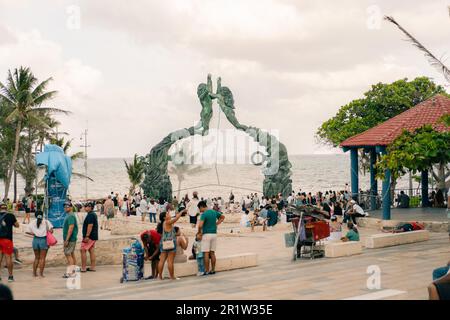 PLAYA DEL CARMEN, MESSICO - maggio 2023 i visitatori si mescolano con gli artisti sotto la scultura di Portal Maya. Foto di alta qualità Foto Stock