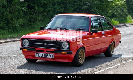 Stoke Goldington, Northants, Regno Unito - Maggio 14th 2023. 1979 ROSSO FORD ESCORT 1600 SPORT auto classica guida attraverso un villaggio inglese Foto Stock