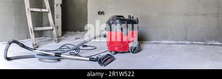 Aspirapolvere industriale rosso nel nuovo cantiere di costruzione della casa, ampio banner fotografico, spazio per testo lato destro Foto Stock