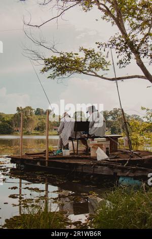 pescatori seduti sulla piattaforma Foto Stock