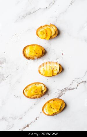 Fette di baguette con formaggio cremoso, persimmon, miele e noci su sfondo marmoreo. Bruschetta antipasti. Sapore dolce salato, ricetta gourmet antipasto Foto Stock