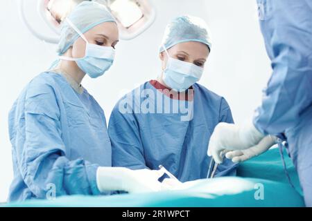 Insegnandole ad un giorno prendere il controllo. Due chirurghi femminili che lavorano insieme durante un intervento chirurgico. Foto Stock