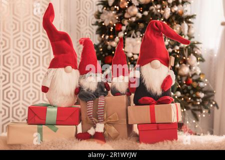 Simpatici gnomi di Natale e scatole regalo sul tappeto in camera Foto Stock