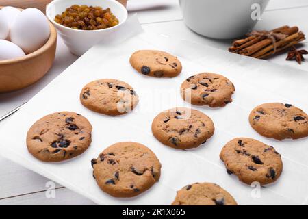 Carta da forno pergamena con gustosi biscotti su tavolo bianco, primo piano Foto Stock