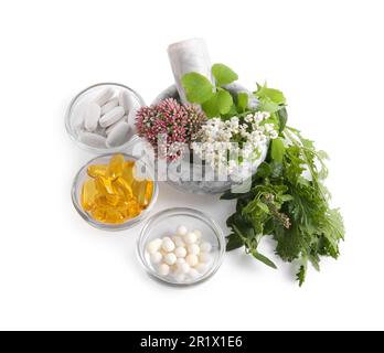 Mortaio di marmo con erbe fresche e pillole su sfondo bianco Foto Stock