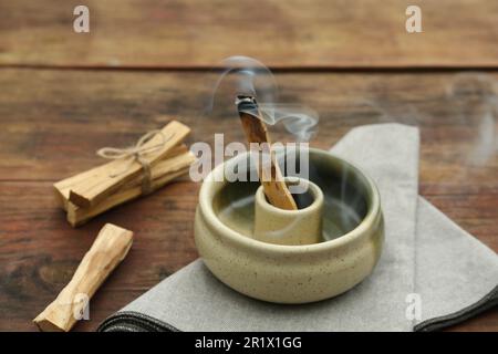 Bastone di palo Santo che frolla in supporto su tavolo di legno Foto Stock