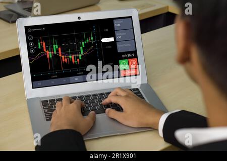 Pianificazione e strategia del giovane uomo d'affari, mercato azionario, commerciante che lavora in ufficio. Grafico e indicatore tecnico dei prezzi, grafico a candele rosso e verde Foto Stock