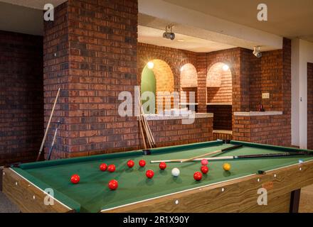 Un tavolo da biliardo con un home bar sullo sfondo nel seminterrato di una grande casa. Questa casa è stata da allora demolita. Foto Stock