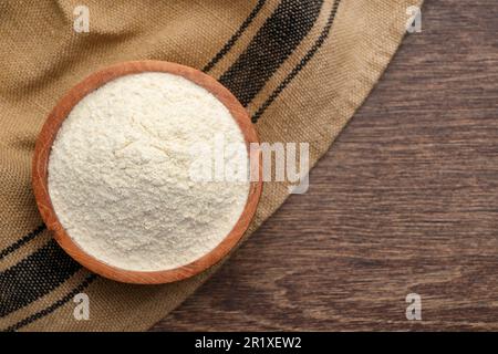 Farina di quinoa biologica in ciotola su tavolo di legno, vista dall'alto. Spazio per il testo Foto Stock