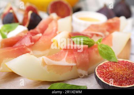 Gustosi meloni, jamon e fichi serviti su asse di legno, primo piano Foto Stock