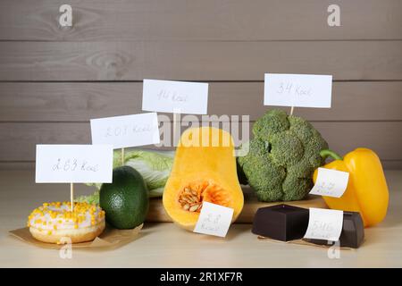 Prodotti alimentari con etichette di potere calorifico su tavola di legno. Concetto di perdita del peso Foto Stock