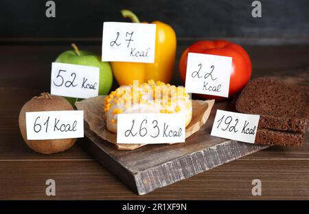 Prodotti alimentari con etichette di potere calorifico su tavola di legno. Concetto di perdita del peso Foto Stock