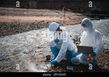 Ecologo di campionamento acqua sostanze chimiche tossiche dal fiume con provetta in vetro e fumo bianco Foto Stock