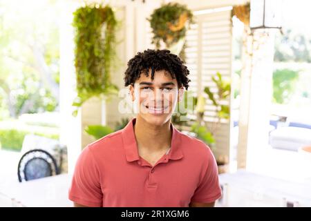 Ritratto di felice uomo biraciale con capelli ricci neri sorridenti a casa in stanza soleggiata Foto Stock