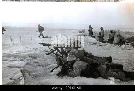 I soldati tedeschi in B&W della seconda guerra mondiale in Snow Camo avanzano con il fuoco di copertura di un Heavy MG Team Foto Stock