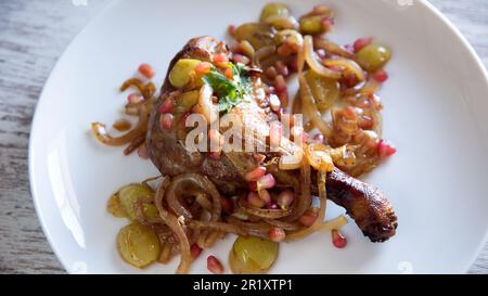 Confit d'anatra con cipolla, melograno e uva. Foto Stock