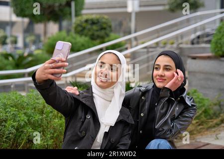 Giovani donne musulmane con hijab che prendono selfie Foto Stock