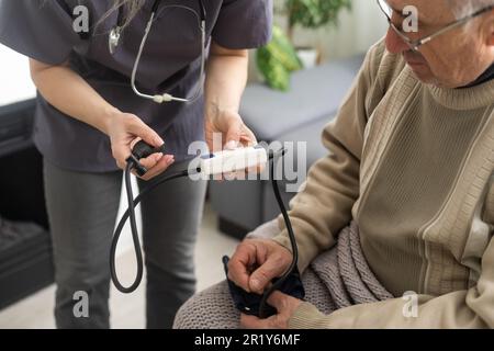 Giovane donna medico indossando uniforme bianca con stetoscopio di controllo della pressione sanguigna del paziente maturo alla riunione in ospedale, medico serio medico medico di uso Foto Stock