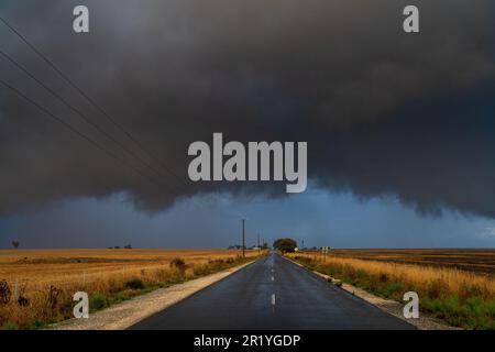 Guardando giù una strada di campagna verso una nube di tempesta oscura che si avvicina a Moolort nel Victoria centrale, Australia Foto Stock