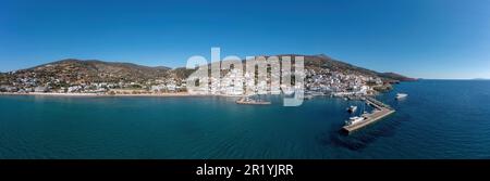 Andros isola, panorama del villaggio di Batsi, Cicladi destinazione Grecia. Vista dalla nave del porto, barca ormeggiata, edificio, mare chiaro, cielo blu. Banner Foto Stock