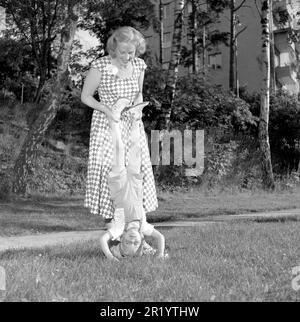 Divertimento negli anni '1950s. Una madre sta giocando con il suo bambino fuori, aiutandolo ad equilibrarsi sulle sue mani e sulla testa. Svezia 5 luglio 1952. Rif. Conard 2066 Foto Stock