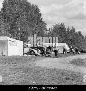 Campeggio nel 1960s. Un campeggio dove le famiglie trascorrono parte delle loro vacanze estive. Le loro auto sono viste sullo sfondo con l'attrezzatura da campeggio trasportato sul portapacchi. Värmland Svezia 1962. rif BV97-10 Foto Stock