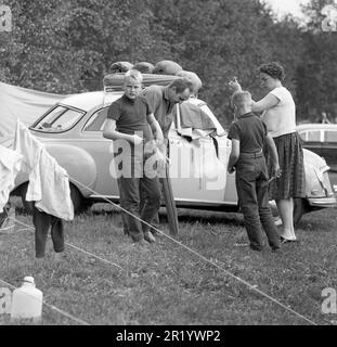 Campeggio nel 1960s. Un campeggio dove questa famiglia trascorre parte delle proprie vacanze estive. La loro auto viene vista sullo sfondo con l'attrezzatura da campeggio trasportata sul portapacchi. Värmland Svezia 1962. rif BV99-7 Foto Stock