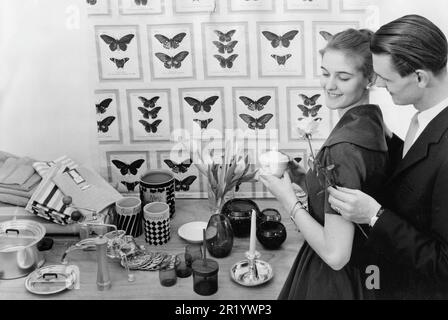 Negli anni '1950s. Un giovane con i tipici oggetti disegnati in 1950s, le applicazioni domestiche e i dettagli su un tavolo di fronte ad essi. Le sta dando una rosa. Svezia 1958 Foto Stock