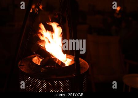 Un fuoco da campeggio ruggente che brucia in una fossa a fiamma aperta, con una pletora di fiamme che leccano all'aria Foto Stock