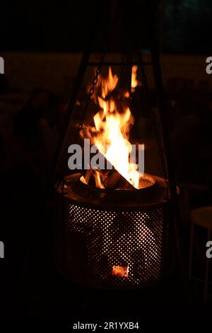 Un fuoco da campeggio ruggente che brucia in una fossa a fiamma aperta, con una pletora di fiamme che leccano all'aria Foto Stock