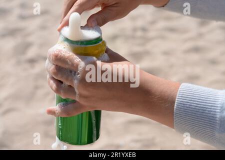 Donna apertura lattina con bevande frizzanti in spiaggia, primo piano Foto Stock