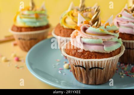 Tortini dolci e carini di unicorno su sfondo giallo, primo piano Foto Stock