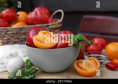 Diversi tipi di pomodori con basilico su tavola di legno Foto Stock